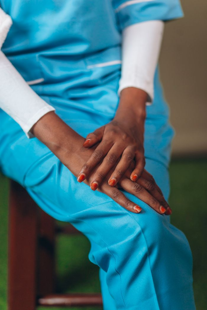 A detail shot of crossed hands in blue medical scrubs, focusing on healthcare professionalism.